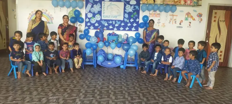 A second photograph of young children dressed in blue with adults, a Blue Day board, and blue balloons.