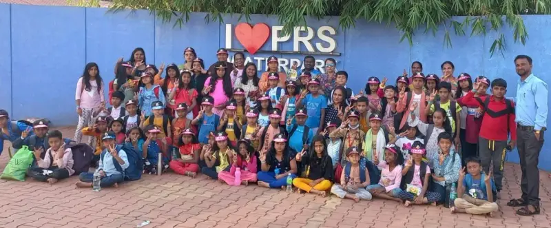 Children and adults sit and stand for a group photograph in front of a wall that reads I love PRS Water Park.